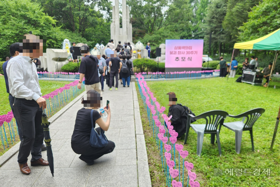 지난 29일 서울 서초구 양재시민의숲에서 진행된 삼풍백화점 붕괴 토토사이트추천 30주기 추모식에서 한 유가족이 희생자인 동생의 이름표 앞에서 사진을 찍고 있다. 이영기 기자.