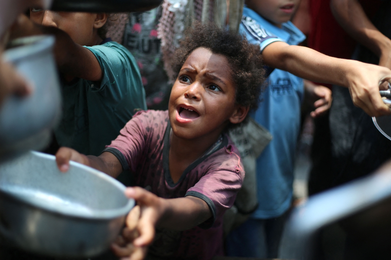 Palestinian children line up to receive a hot meal at a food distribution point in Nuseirat of the Gaza Strip, Monday.    AFP-Yonhap