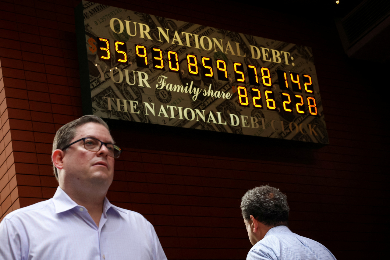 People pass by the National Debt Clock in New York City,  July 1.  Reuters-Yonhap