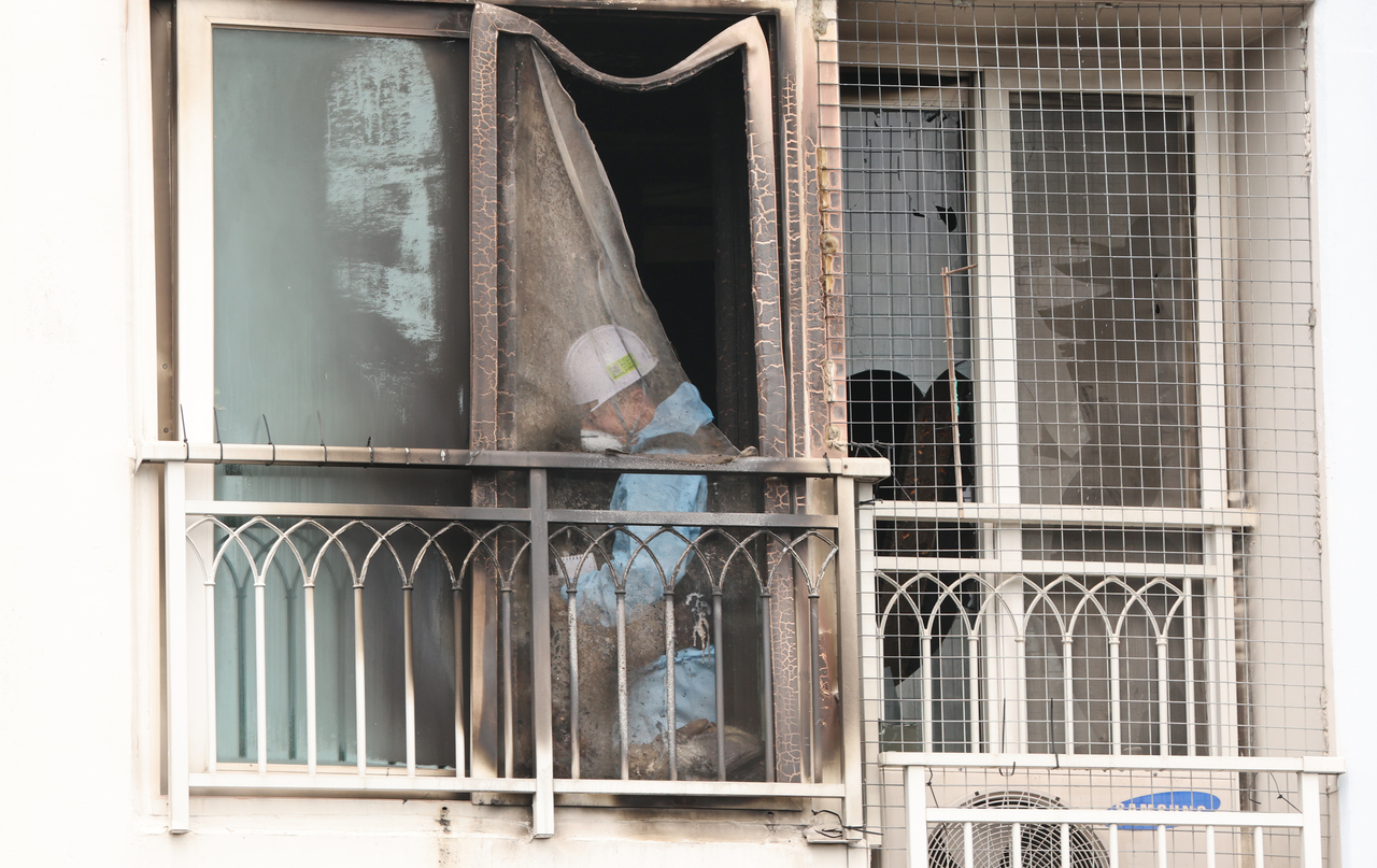 A government official is examining the site of an apartment fire that occurred in Busan on Wednesday night, which killed two young girls aged 8 and 6. (Yonhap)