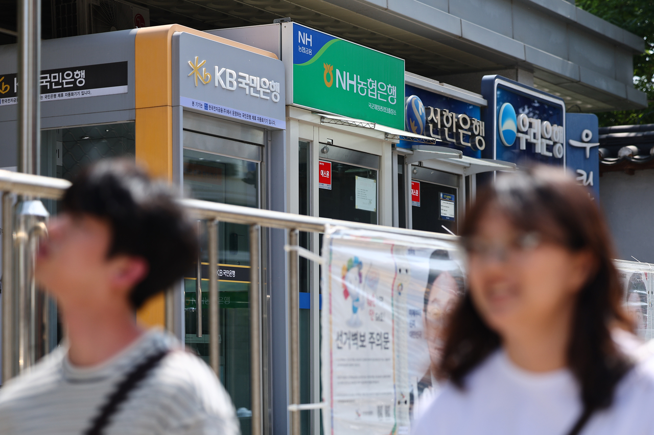 Pedestrians pass by local banks' ATM vestibules on June 3. (Yonhap)