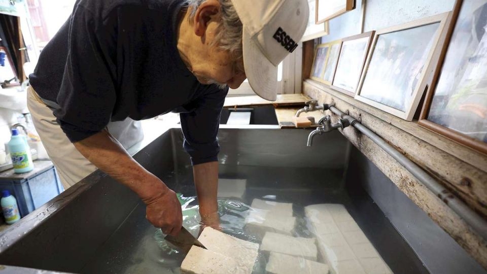 Yoshiaki Ishikawa cuts tofu made using the traditional kamadaki method at Echigoya in Chiyoda ward, Tokyo.    (Japan News)