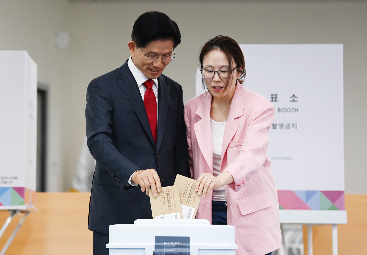 Kim Moon-soo, the presidential candidate of the People Power Party, and his daughter Dong-joo, cast their ballots at a polling station in Incheon on Thursday.  (Lee Sang-sub/The Korea Herald)