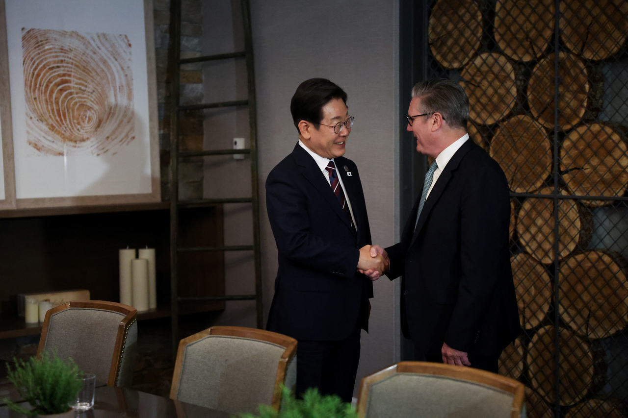 President Lee and British Prime Minister Keir Starmer shake hands as they meet for a bilateral meeting during the G7 Leaders' Summit in Kananaskis, in Alberta, Canada, Tuesday. (Reuters-Yonhap)
