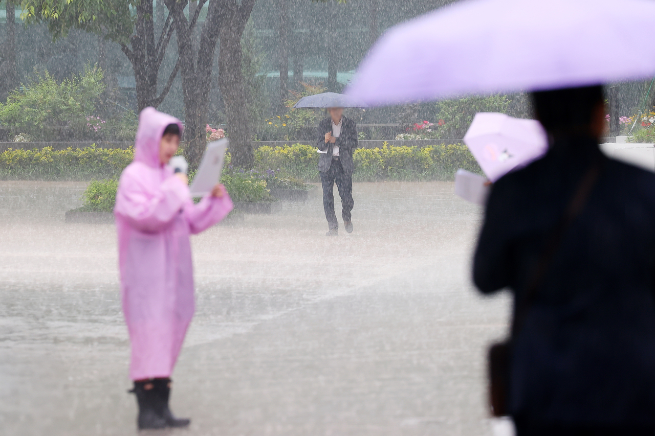 A woman in a raincoat is seen amid heavy rain near Seoul's Gwanghwamun Sqaure on Friday. (Yonhap)