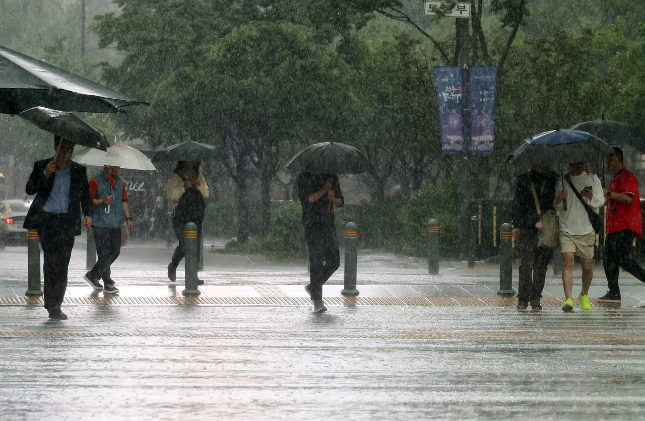 People walk with umbrellas near Gwanghwamun Square in Seoul on Friday. (Yonhap)