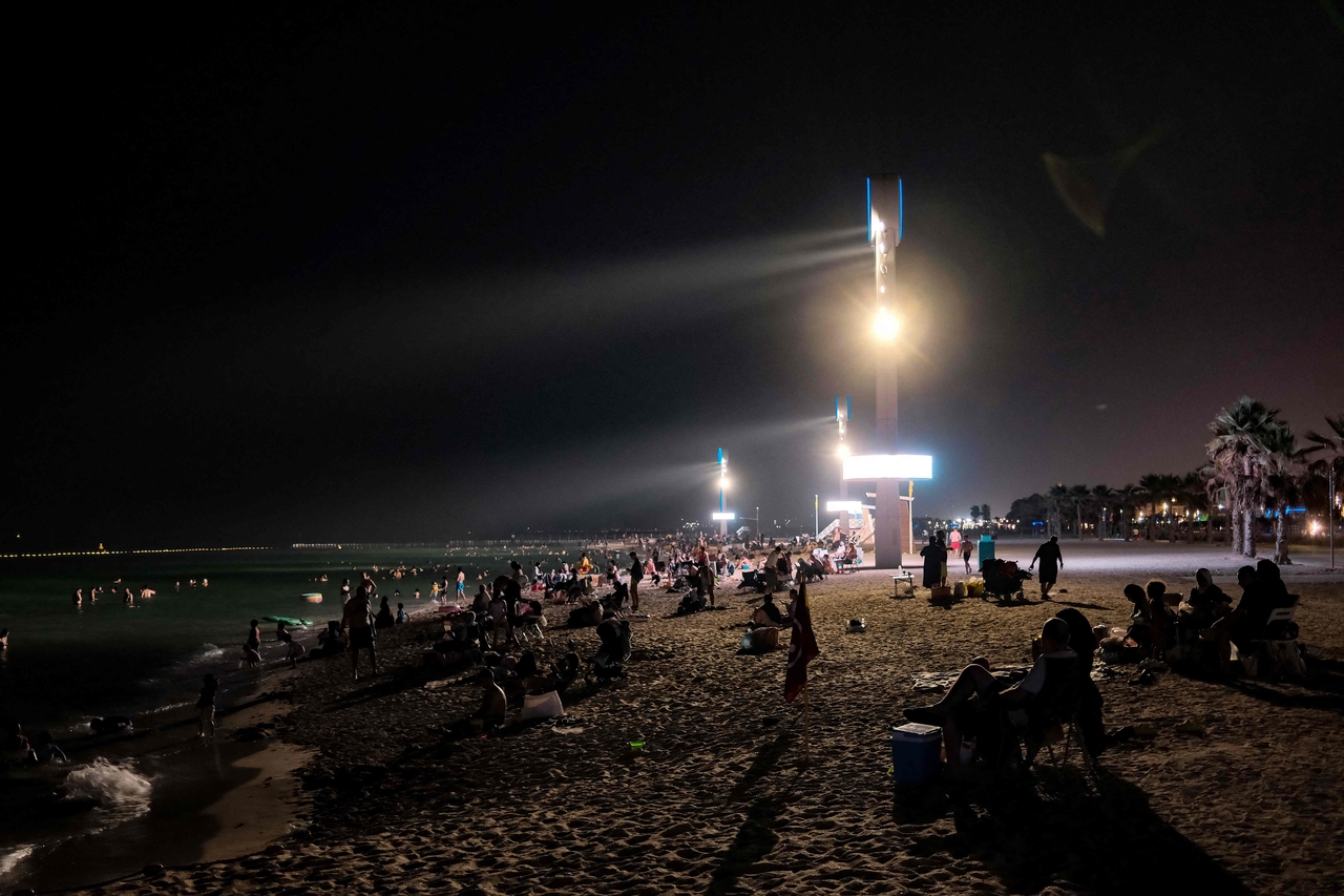 Floodlights illuminate the Umm Suqeim beach in Dubai as people cool off at night, Friday. (AFP-Yonhap)