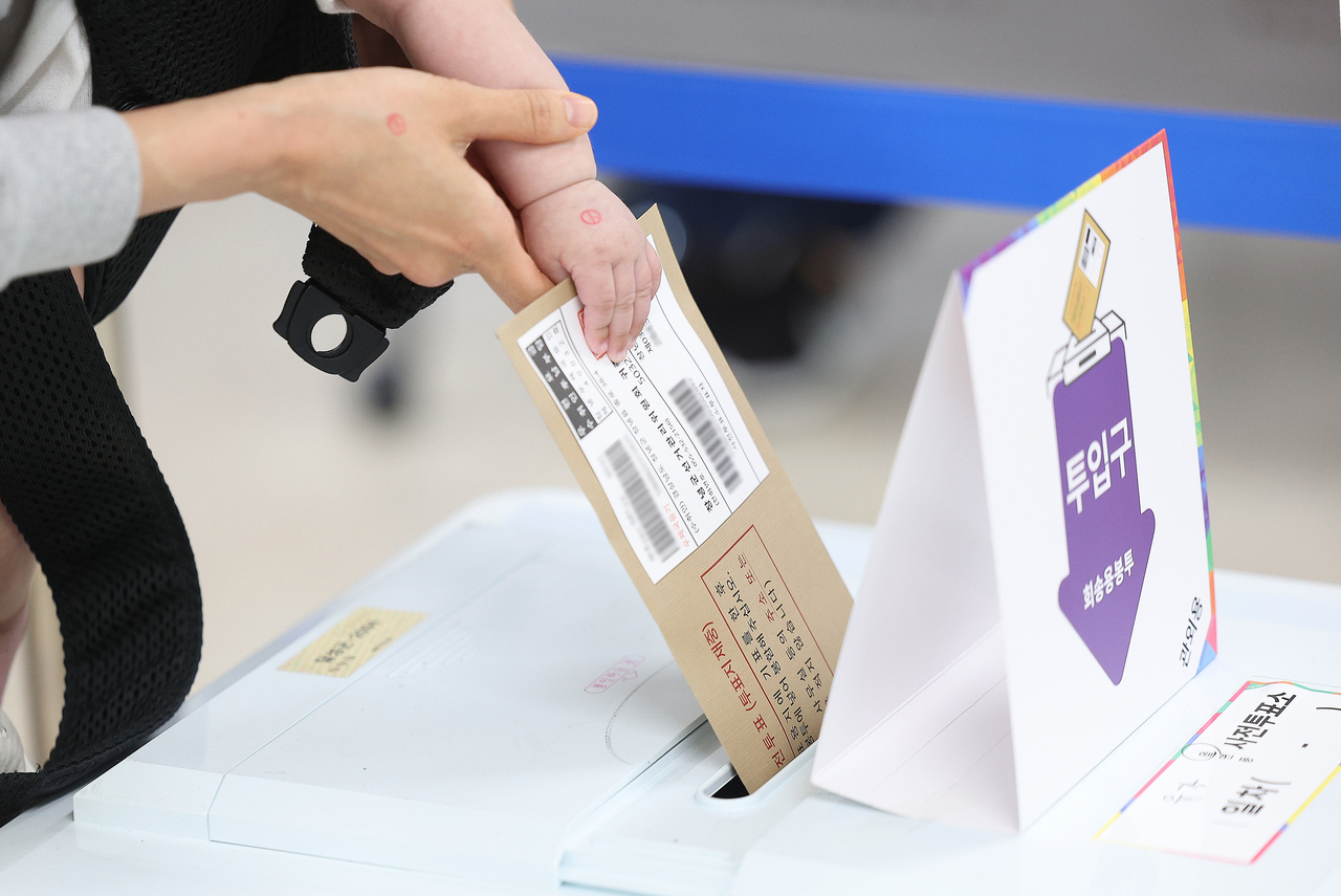 A voter casts a ballot with their child on Thursday at a polling station in Daegu on the first day of early voting in Korea's 21st presidential election. (Yonhap)