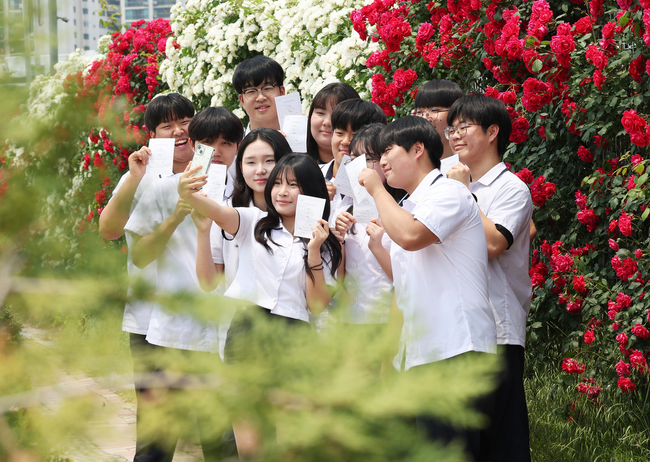 Third-year students from Samil Technical High School take photos after casting their ballots at a polling station set up at the Yeonmu-dong Community Service Center in Suwon, Gyeonggi Province on Thursday. (Yonhap)