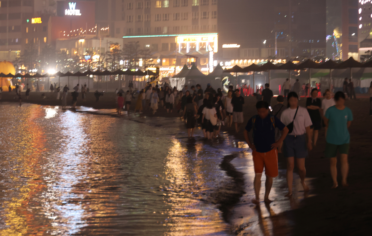 People walk along Gwangalli Beach in Busan, southeastern South Korea, on Monday amid the prolonged heat wave and tropical nights. (Yonhap)