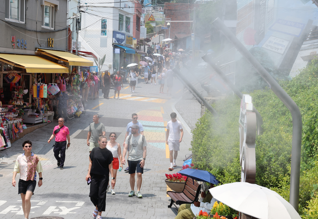 Foreign visitors cool off in sweltering weather in the southeastern port city of Busan on Tuesday, as most parts of the country remain under extreme heat warnings or advisories. (Yonhap)