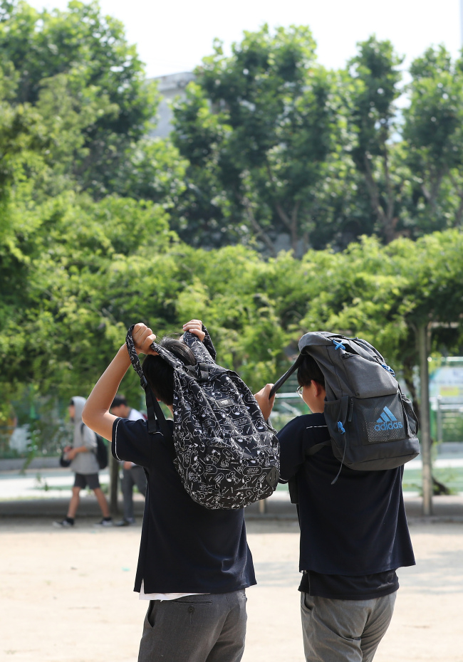 대구시 수성구 한 중해외 토토사이트 순의에서 단축수업을 마친 학생들이 가방으로 햇볕을 가리고 있다. [연합]