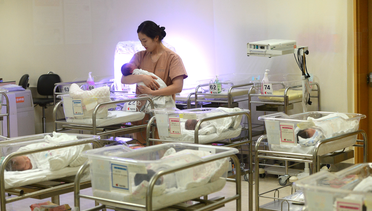 Newborns rest in bassinets as a nurse provides care at Ain Hospital located in Incheon. (Newsis)