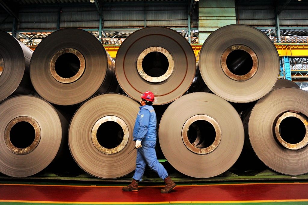 A worker walks by unfinished rolls of stainless steel in a Posco subsidiary in Qingdao city in China's Shandong province. (Getty Images)