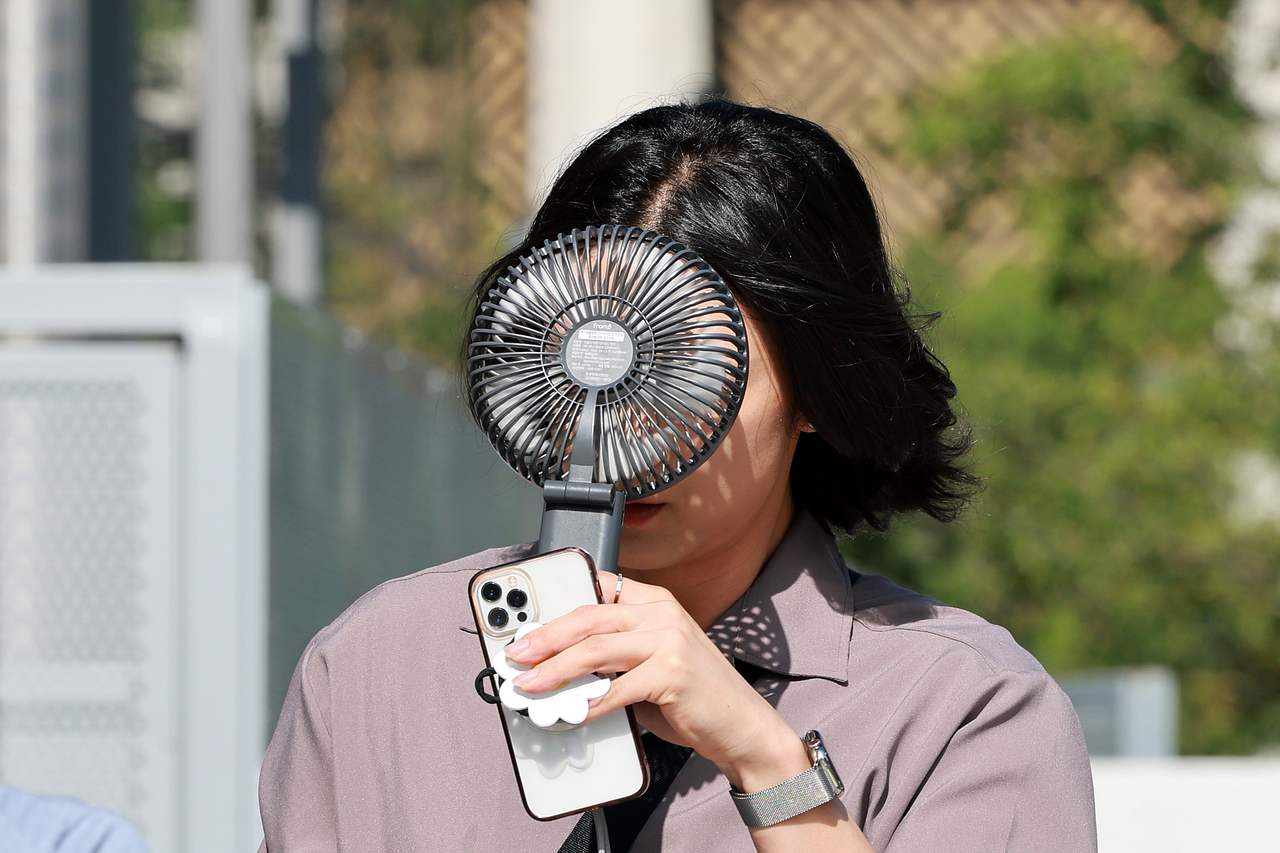 A pedestrian walks with a portable fan at Jongno-gu, central Seoul, Thursday, as the capital city saw temperatures reach as high as 37 degrees Celsius that day.