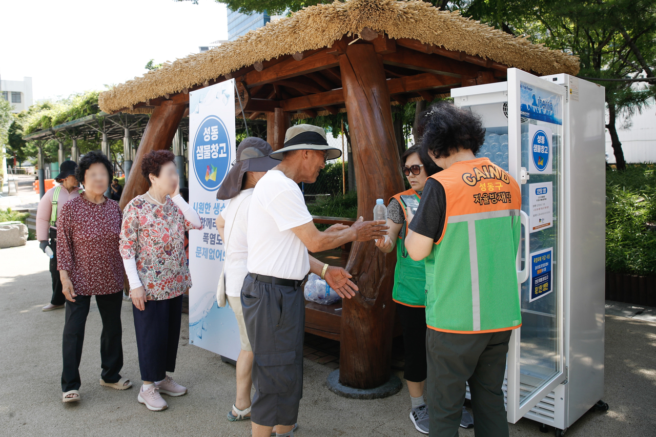 Senior citizens receive free bottled water from  Seongdong-gu's free water refrigerator on Thursday. (Seongdong-gu Office)