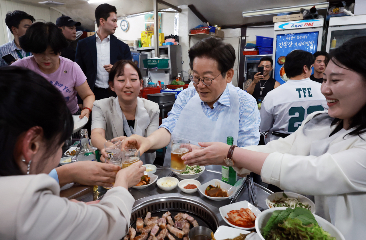 President Lee Jae-myung makes a toast with citizens at a Korean restaurant near Gwanghwamun, central Seoul, on Thursday evening. (Yonhap)