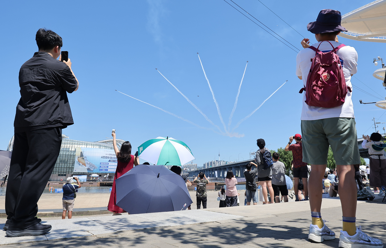 People watch the South Korean Air Force’s Black Eagles aerobatic team perform a celebratory flight marking the inaugural K-Defense Day, observed annually on July 8, at Banpo Hangang Park in southern Seoul on Saturday. (Yonhap)