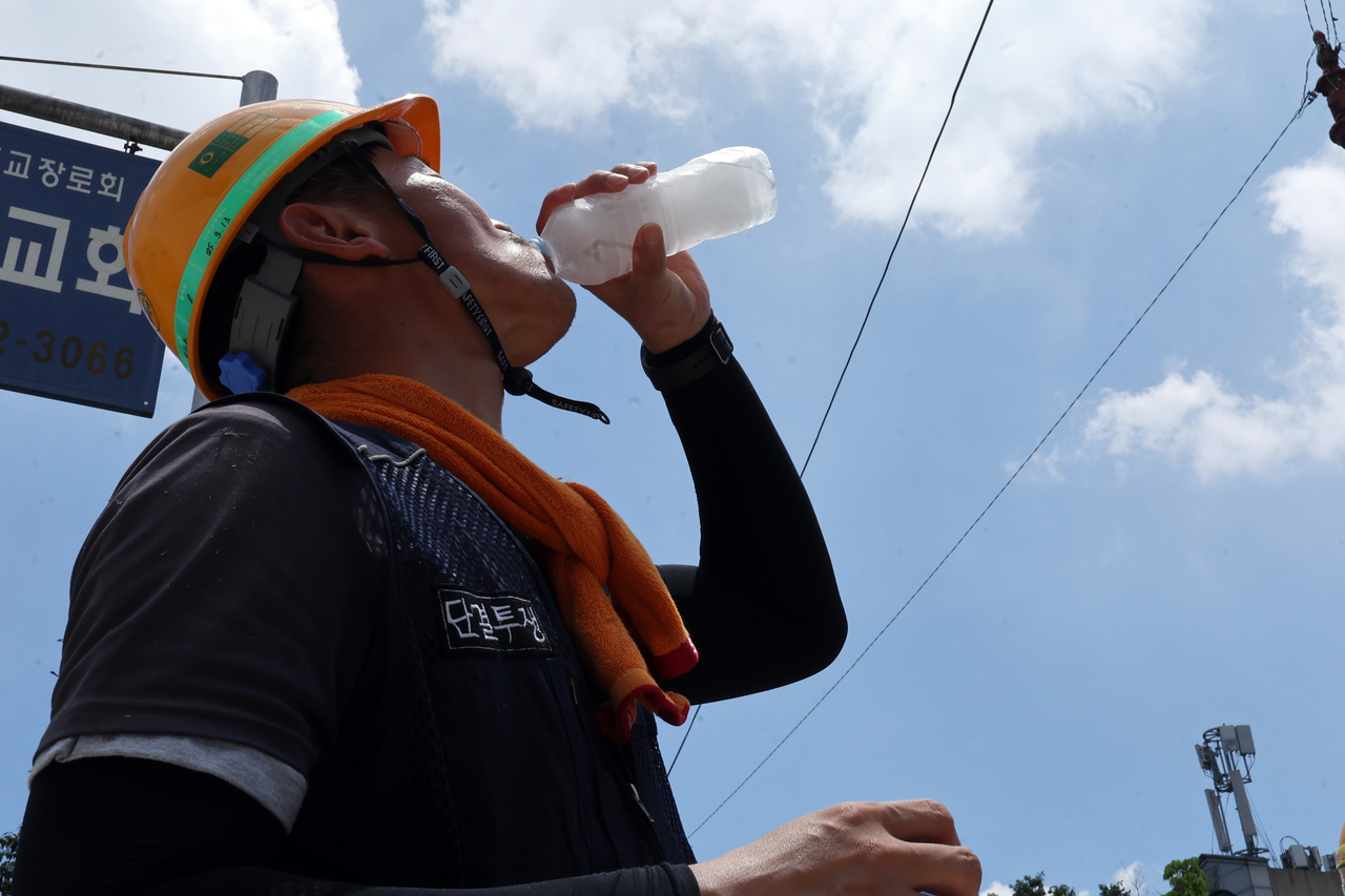 A construction worker in Gwangju drinks water while working at a construction site on July 2. (Yonhap)