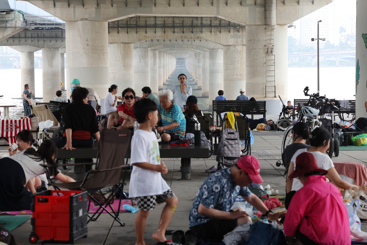 People escape the rain and enjoy a summer break under Mapo Bridge in Seoul on Sunday. (Yonhap)