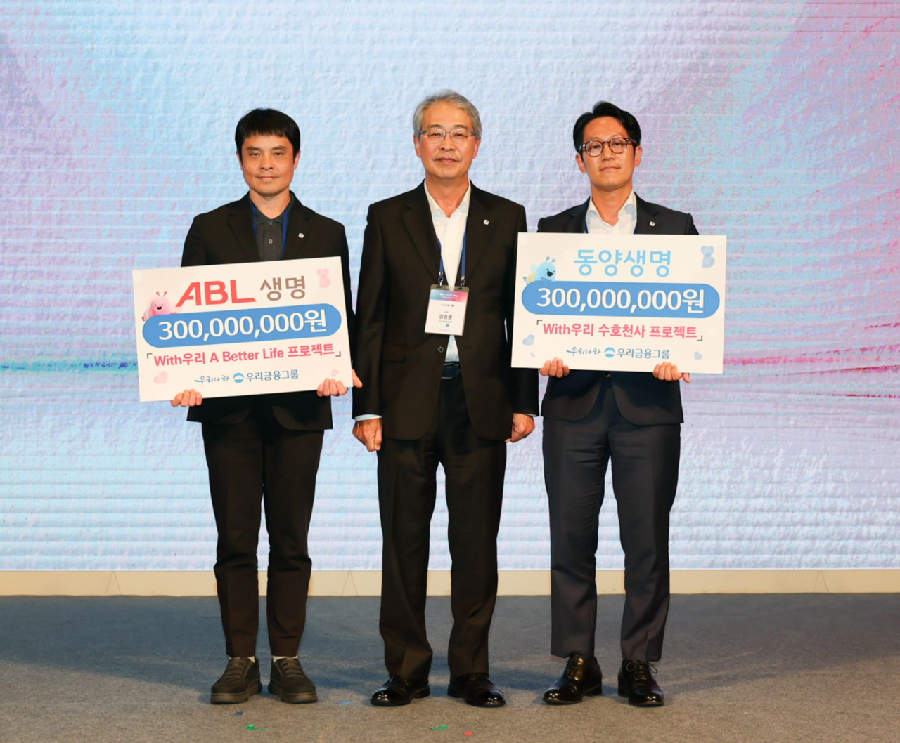 Woori Financial Group Chairman Yim Jong-ryong (center) presents project funding to corporate social responsibility representatives from Tongyang and ABL Life at the Woori WON Day event held in Yongsan, Seoul, Friday. (Woori Financial Group)