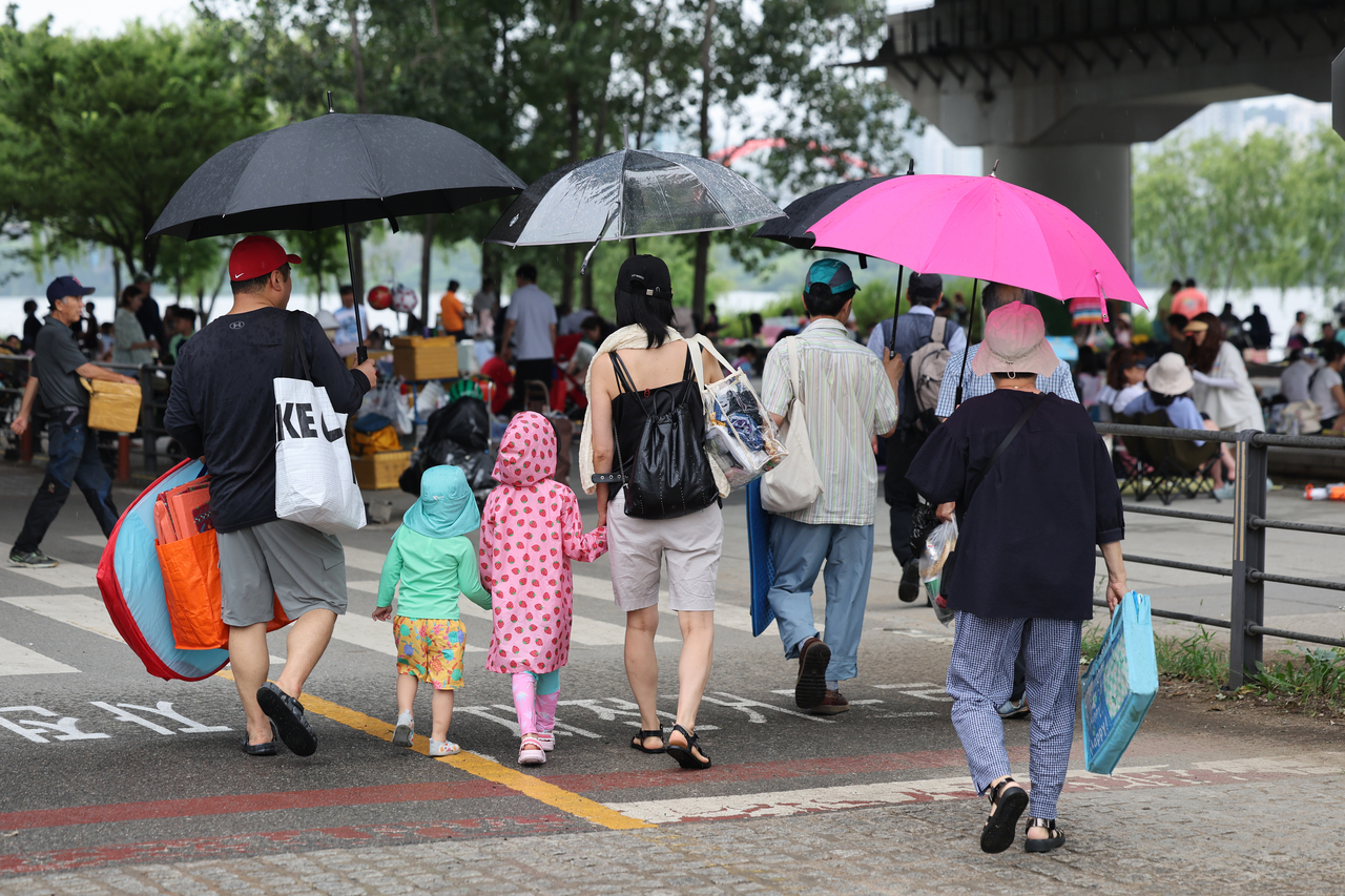 People move to avoid the rain while enjoying playing in water in Yeouido, Seoul, on Sunday. (Yonhap)
