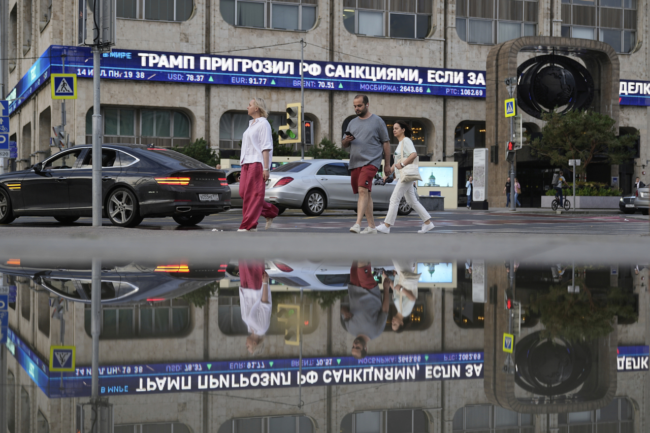 People cross a street as a news ticker installed on the facade of TASS news agency building reports on US President Donald Trump threatening Russia with new tariffs in Moscow on Monday.   AP-Yonhap