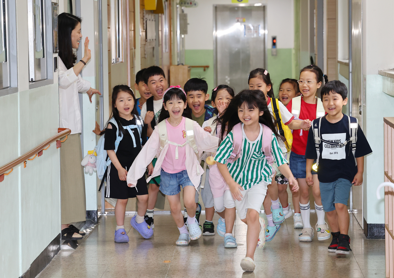 First graders at Buil Elementary School in Bupyeong-gu, Incheon, hurry out of their classroom with excitement after the completion of their summer break ceremony on Tuesday. (Yonhap)