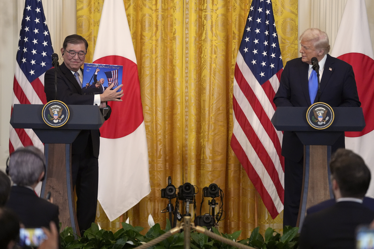 토토사이트 신고보상 시게루 일본 총리(왼쪽)가 7일(현지시간) 미국 워싱턴 백악관에서 열린 기자 회견에서 도널드 트럼프 대통령이 선물한 책을 들고 있다. AP]