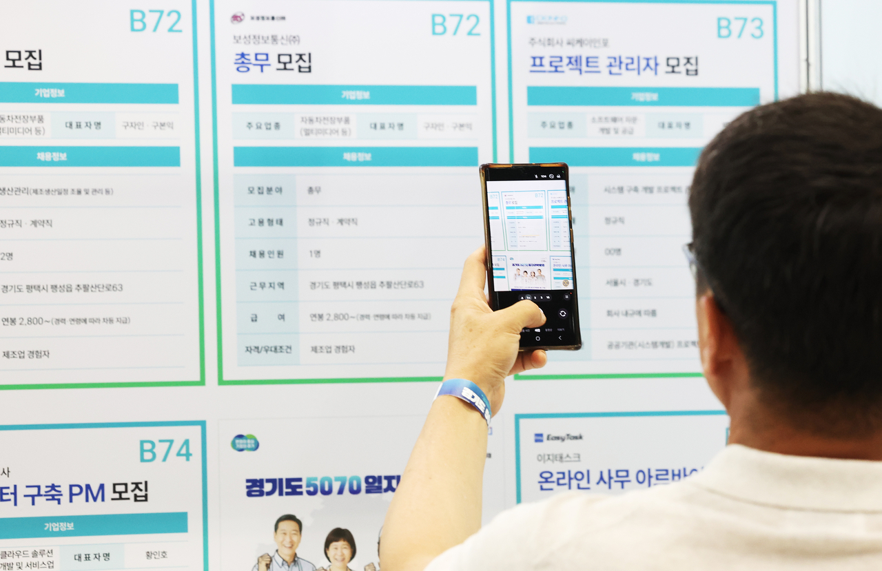 A job seeker photographs a recruitment board at a job fair with his phone at the Gyeonggi-do 5070 Job Fair held at Suwon Messe in Gwonseon-gu, Suwon, Gyeonggi Province, on July 9. (Yonhap)