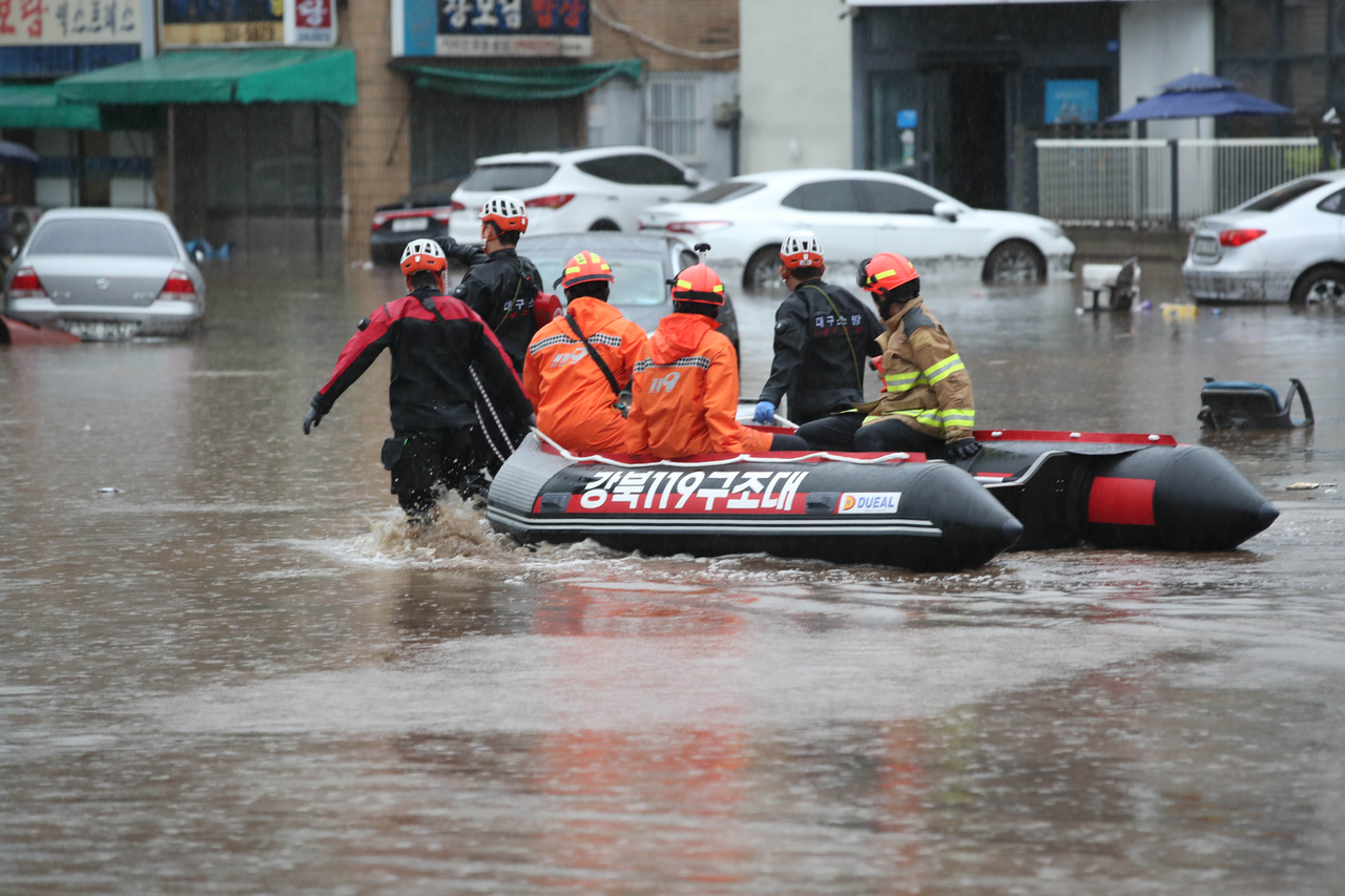 Rescue workers aboard a boat search for people in the flooded Nogeok-dong area of Buk-gu, Daegu, after a sudden downpour submerged parts of the neighborhood on Friday. (Yonhap)