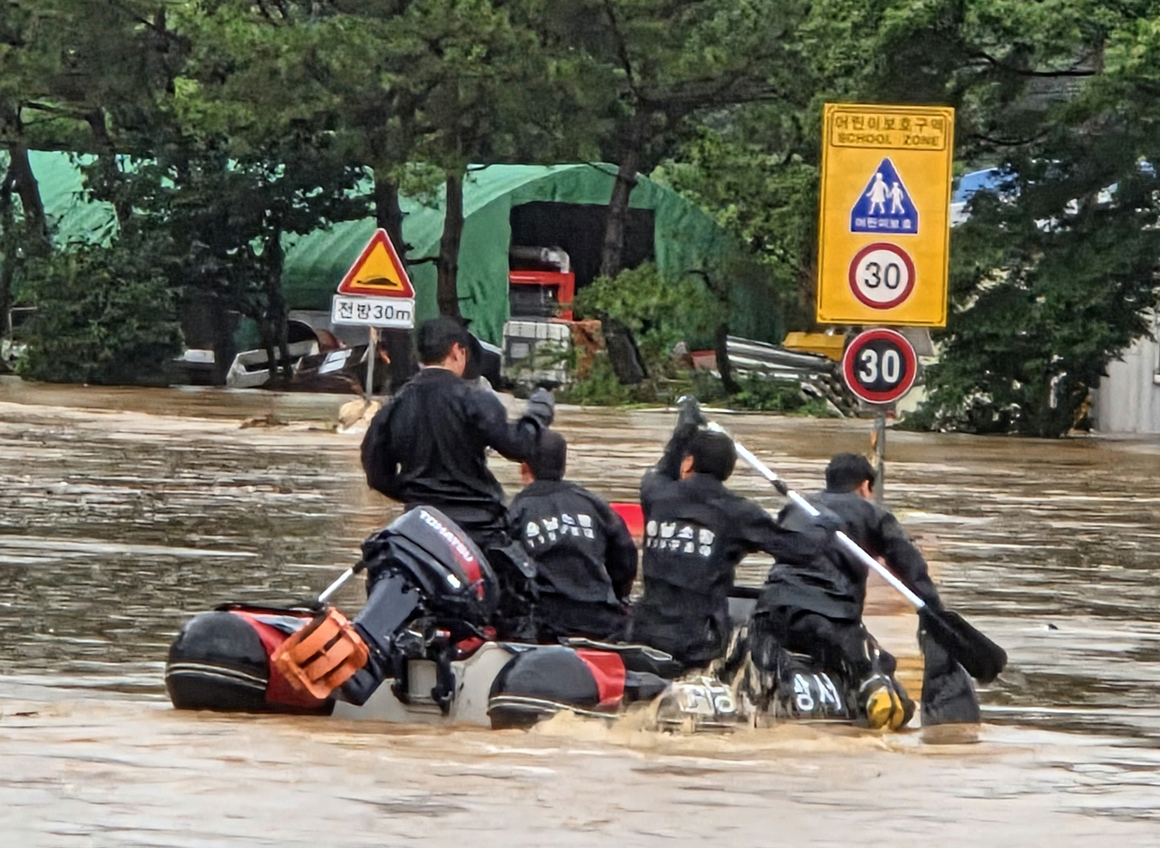Firefighters paddle a rescue boat through floodwaters in Yongyeon-dong, Dangjin, South Chungcheong Province, on Thursday. (Yonhap)