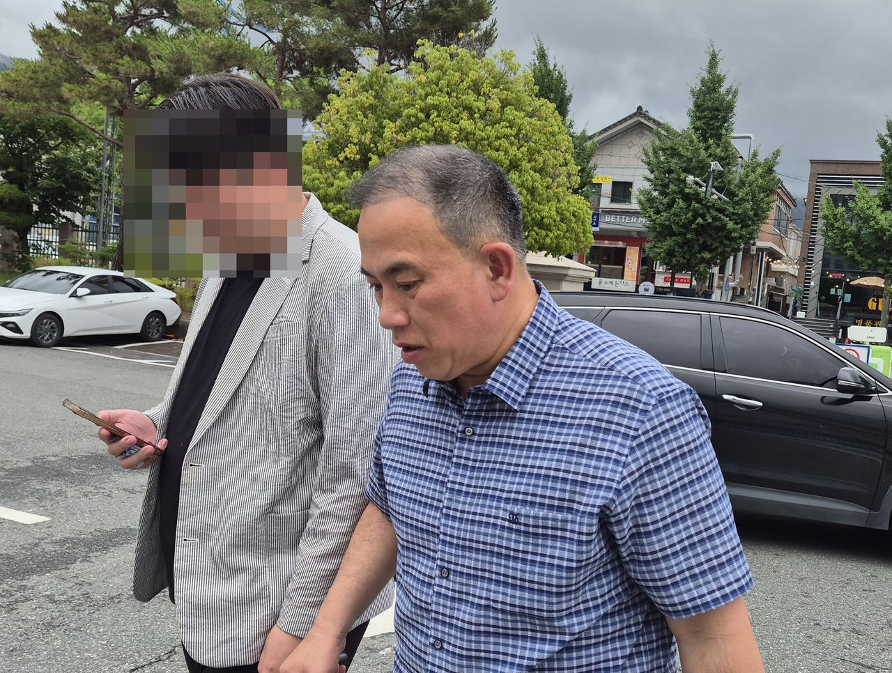 Myung Tae-kyun (right) arrives at the Changwon Jungbu Police Station in Changwon, South Gyeongsang Province, on June 20. (Yonhap)