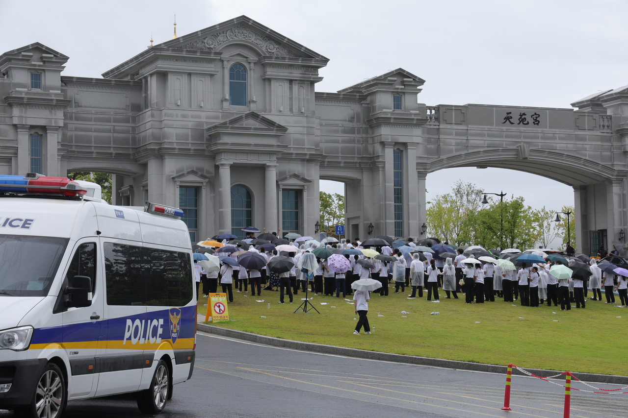 Special counsel team investigators raid the Unification Church's global headquarters in Gapyeong, Gyeonggi Province, on Friday as part of its probe into several allegations surrounding former first lady Kim Keon Hee. In this photo, members of the church are seen protesting against the raid outside its Gapyeong headquarters. Yonhap