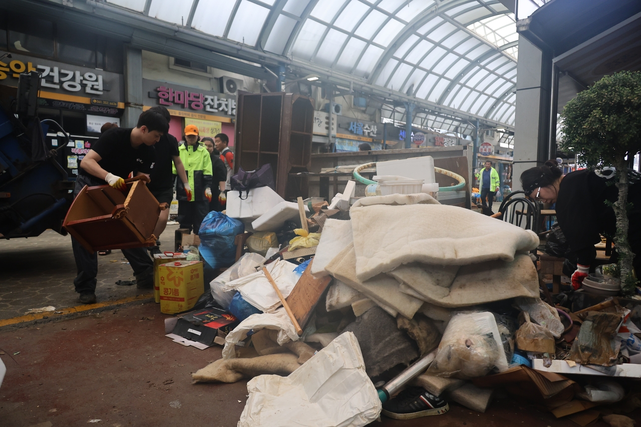 Piles of soaked furniture and waste are removed from shops in Dangjin’s traditional market on Friday after torrential rains flooded the area. (Yonhap)