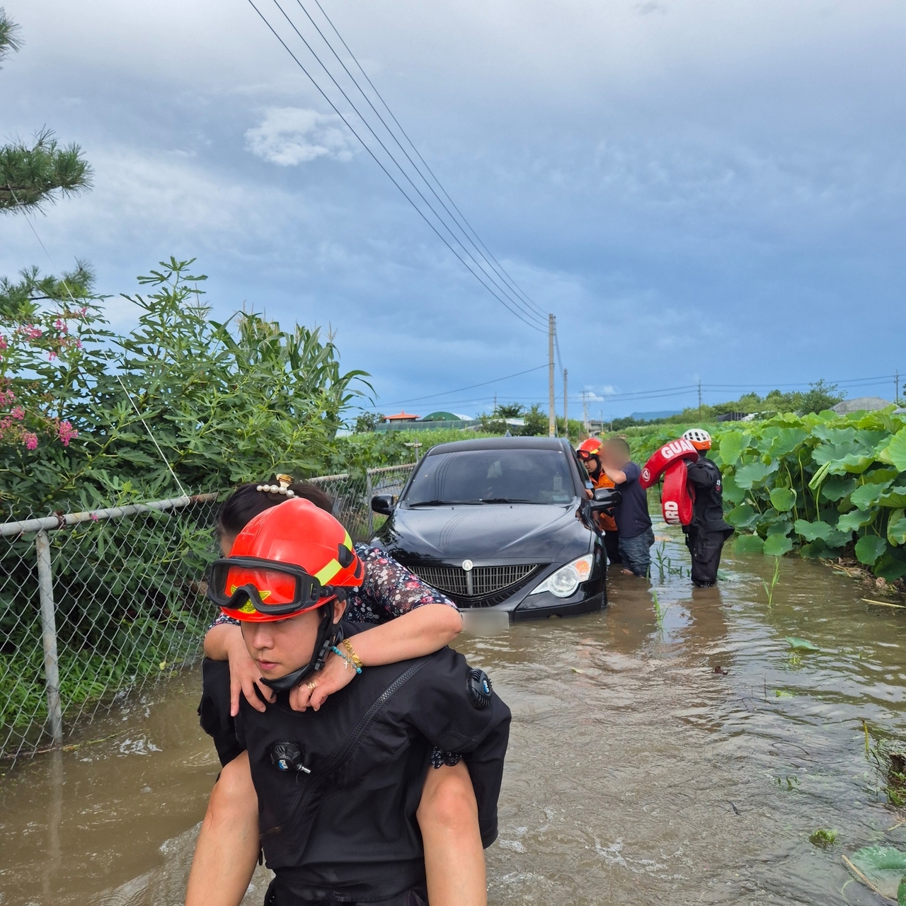 A firefighter carries a woman on his back through a flooded village in Uiryeong County, South Gyeongsang Province, on Friday after heavy downpours. (Yonhap)