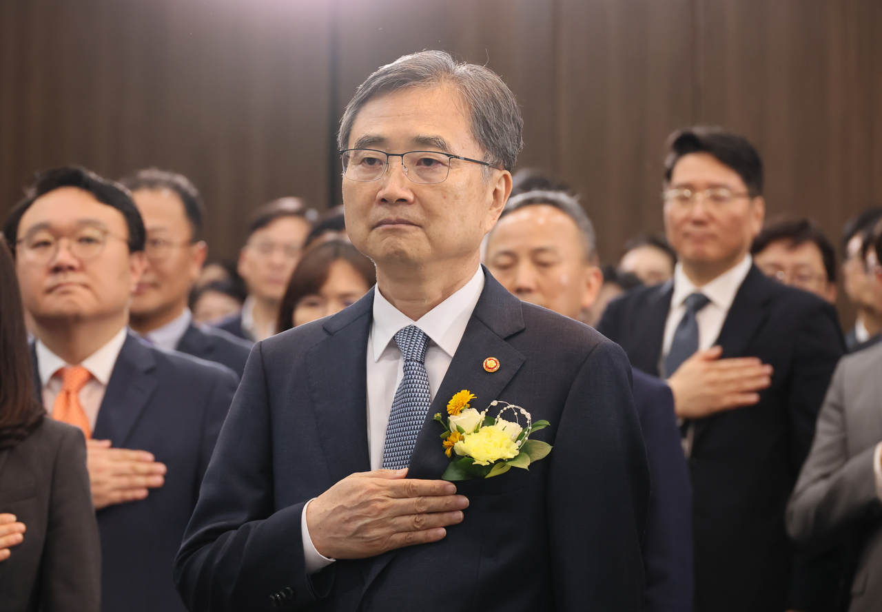South Korea's new Foreign Minister Cho Hyun stands with his hand over his heart as he faces the national flag during a ceremony to mark his inauguration at the Foreign Ministry in Seoul on Monday. (Yonhap)