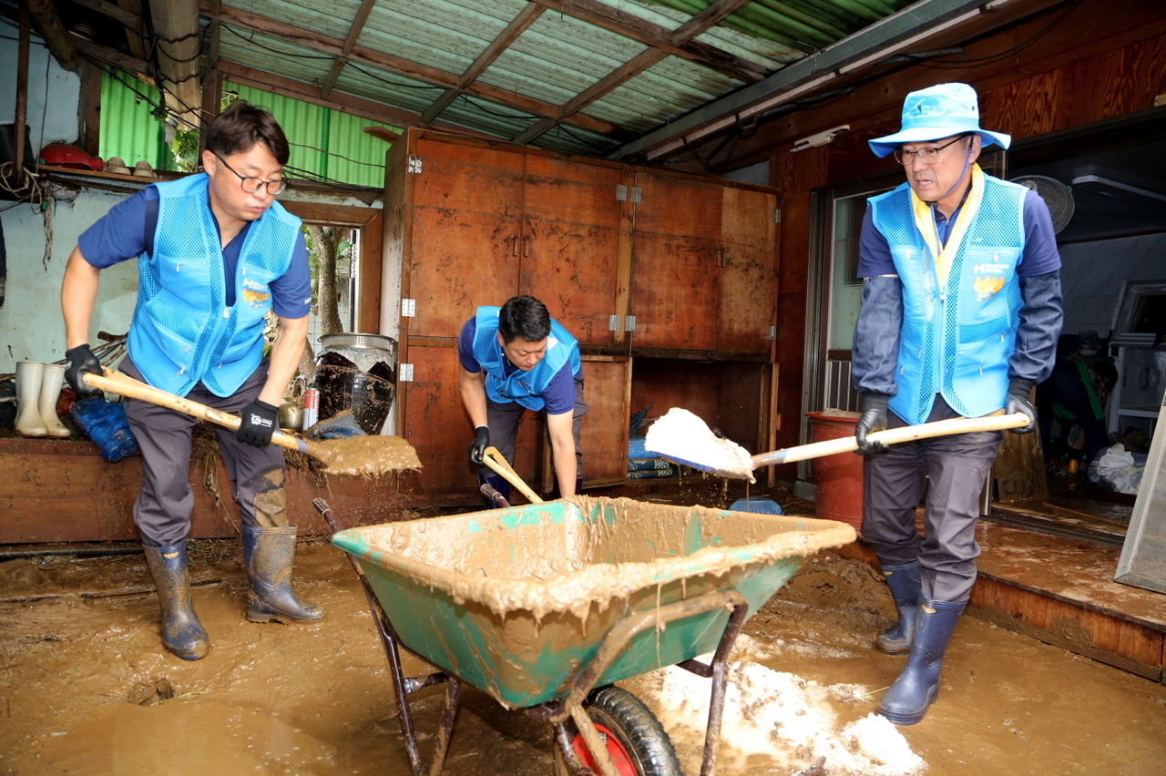 Hyundai Steel employees and Majungmul volunteer group members clear mud and remove damaged items during flood recovery in Yongyeon-dong, Dangjin, South Chungcheong Province, Friday. (Yonhap)