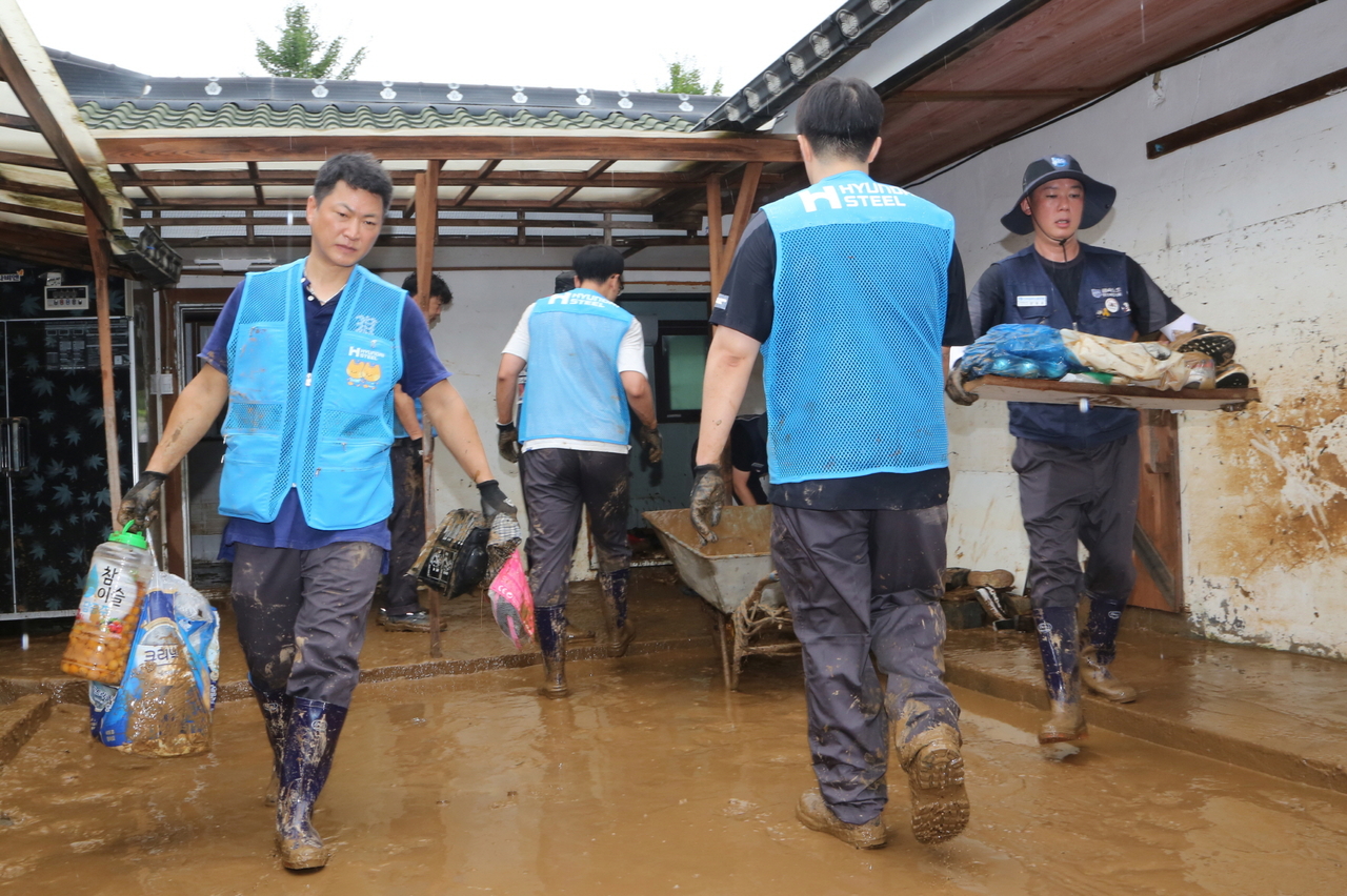 Hyundai Steel workers and Majungmul volunteers remove mud and damaged items during flood recovery in Yongyeon-dong, Dangjin, South Chungcheong Province,  Friday. (Yonhap)