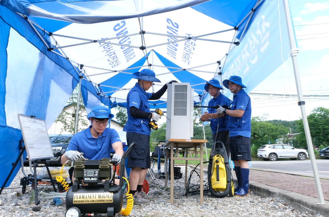 Samsung Electronics employees inspect and repair damaged home appliances in a flood-hit area. (Samsung Electronics)