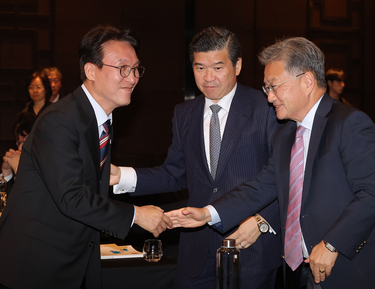 South Korean Prime Minister Kim Min-seok (left) shakes hands with Joseph Yun, charge d'affaires at the US Embassy in Korea, after delivering his keynote speech at the American Chamber of Commerce in Korea seminar held at Conrad Seoul in Yeouido on Tuesday. AmCham Chair James Kim stands in the center. (Yonhap)