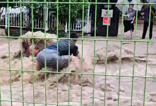 This photo shows Choi Seung-il helping a man whose leg was stuck inside a manhole during a flood in Gwangju on Thursday. (Yonhap)