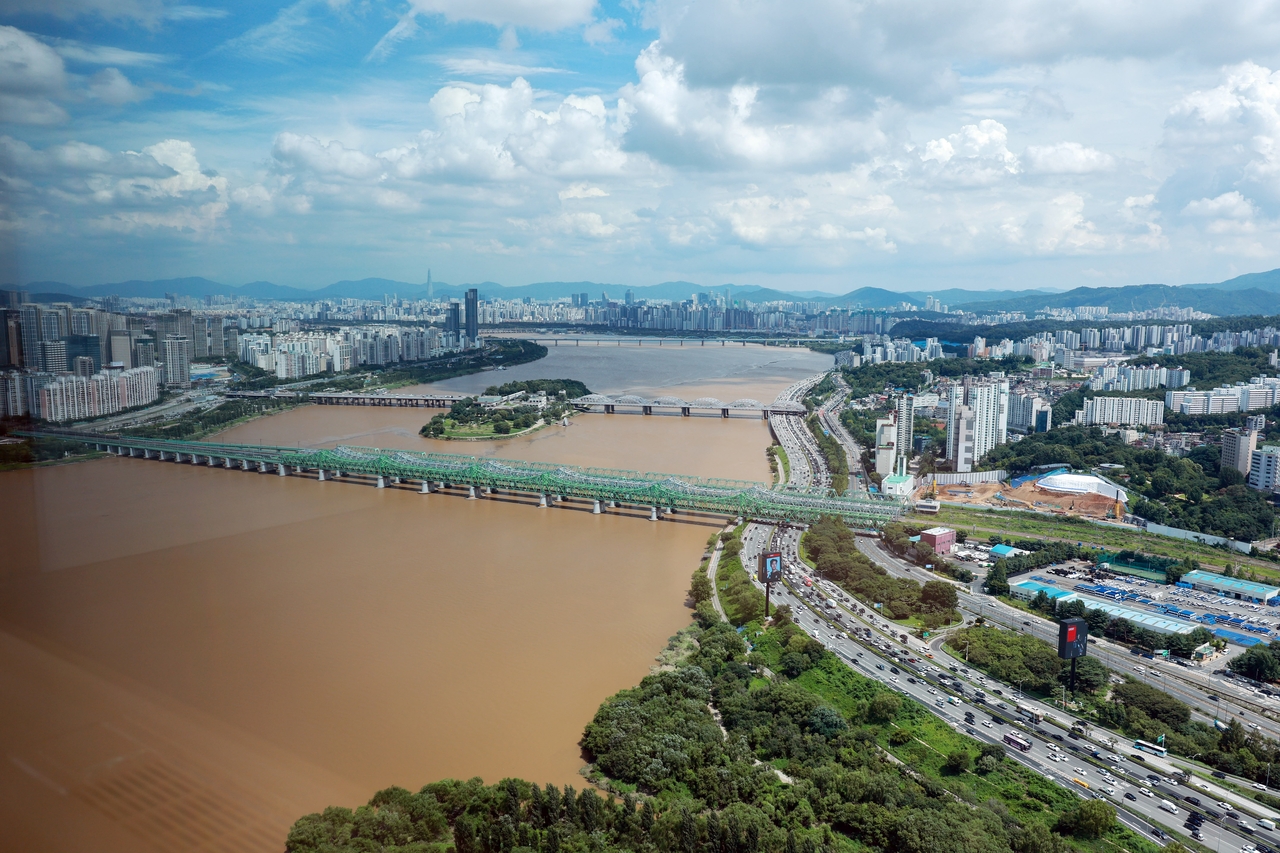 The Han River flows muddy and brown around Hangang Bridge and Nodeul Island in Seoul on Tuesday following days of extremely heavy rainfall. (Yonhap)