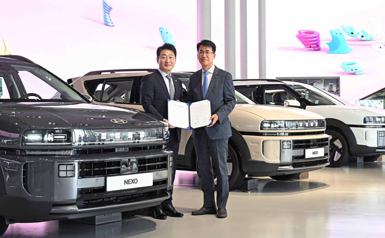 Kim Dong-wook (right), head of strategy planning division at Hyundai Motor Group, and Lee Ho-hyun, 2nd Vice Minister of Trade, Industry and Energy, pose for a photo next to Hyundai Motor's hydrogen-powered Nexo vehicles at Hyundai Motor Studio Goyang in Gyeonggi Province on Tuesday. (Hyundai Motor Group)