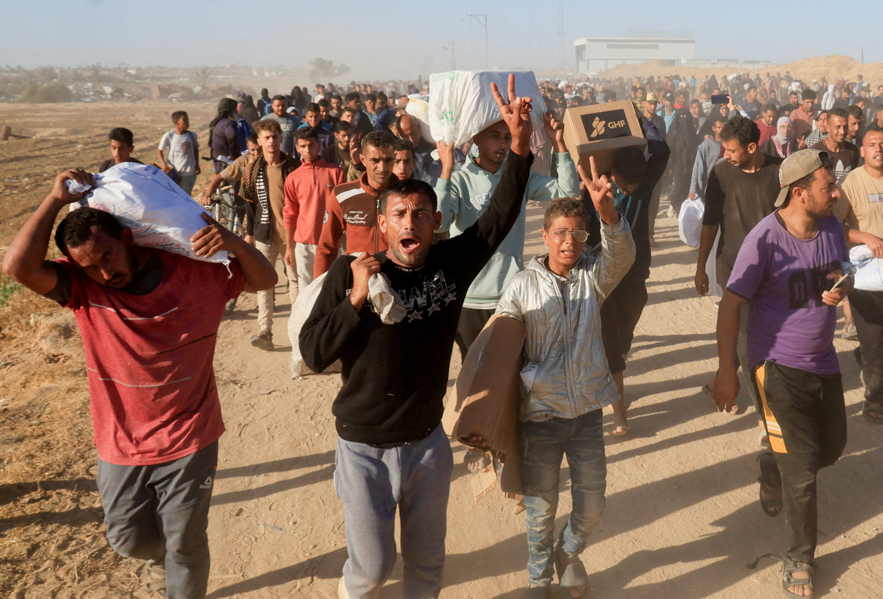 Palestinians carry aid supplies from the US-backed Gaza Humanitarian Foundation, in Khan Younis, Gaza Strip, in May. (Reuters-Yonhap)