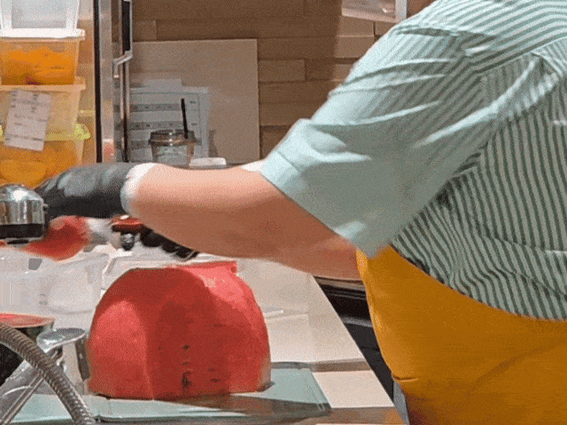 A member of staff cuts a watermelon at a Fresh Table station at The Hyundai Seoul department store in Yeouido, Seoul. (Song Seung-hyun/The Korea Herald)