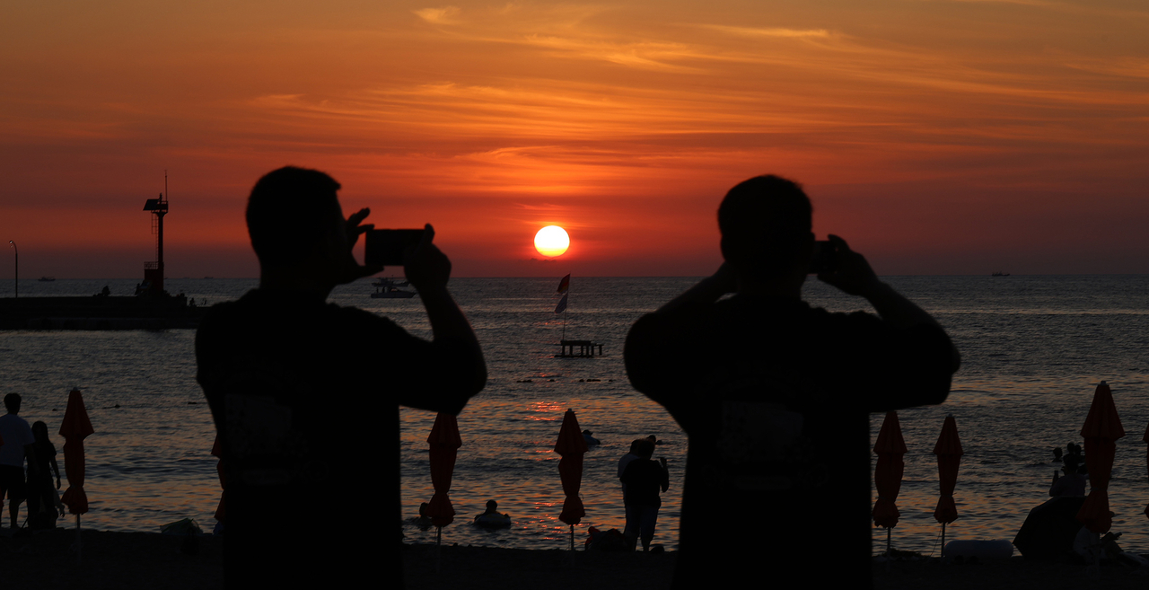 Visitors at Ihoteu Beach in Jeju Island photograph the sunset on Wednesday, when temperatures reached as high as 31.5 C. (Yonhap)