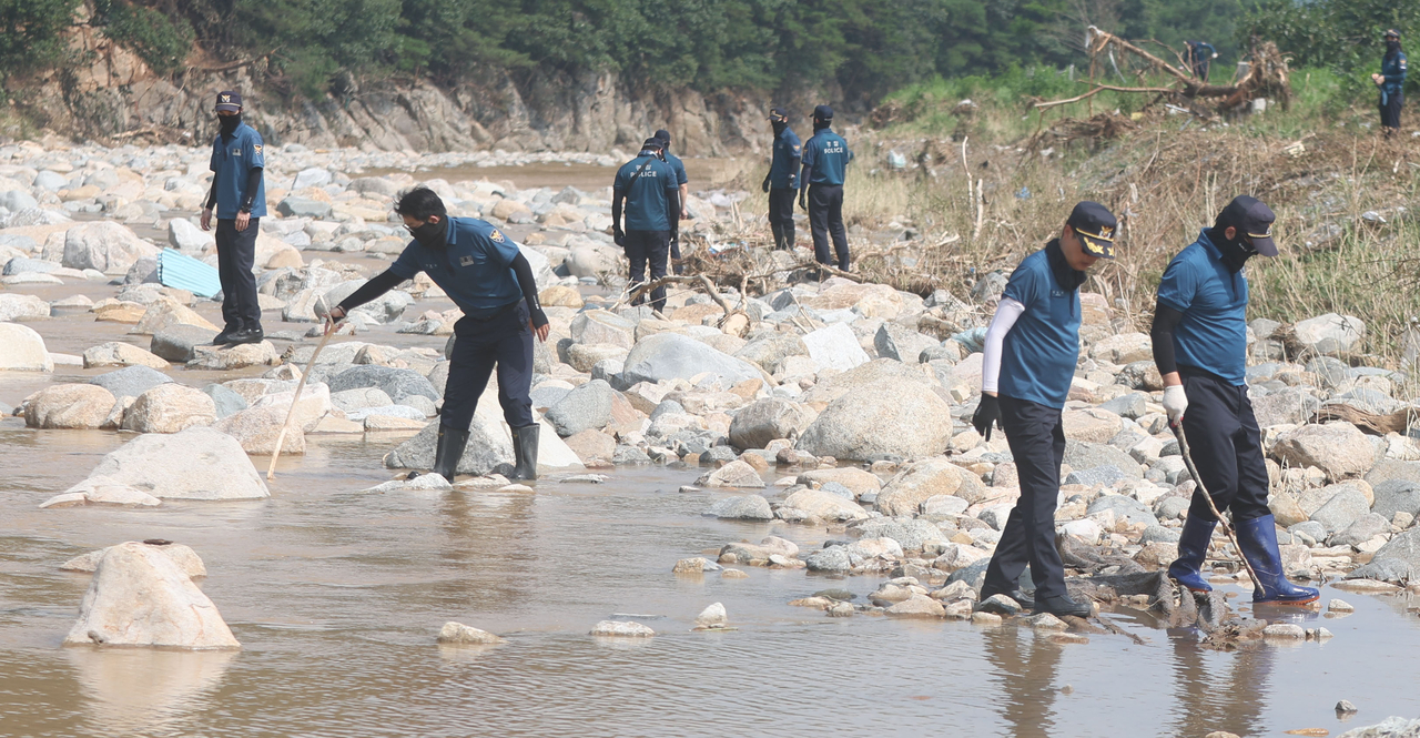 Police search for a missing resident at a riverside in Sancheong, South Gyeongsang Province, on Wednesday. (Yonhap)