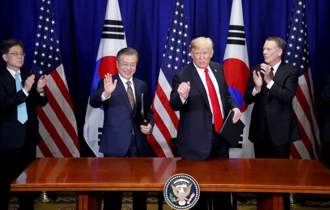 문재인 대통령과 도널드 트럼프 미국 대통령이 2018년 9월 24일 오후 (현지시간) 미국 뉴욕 롯데 뉴욕팰리스 호텔에서 열린 ‘한미 자유무역협정(FTA) 서명식’을 마친 뒤 취재진에게 손을 들어 보이고 있다. 당시 김현종(왼쪽 첫번째) 통상교섭본부장이 박수를 치고 있다. [연합]