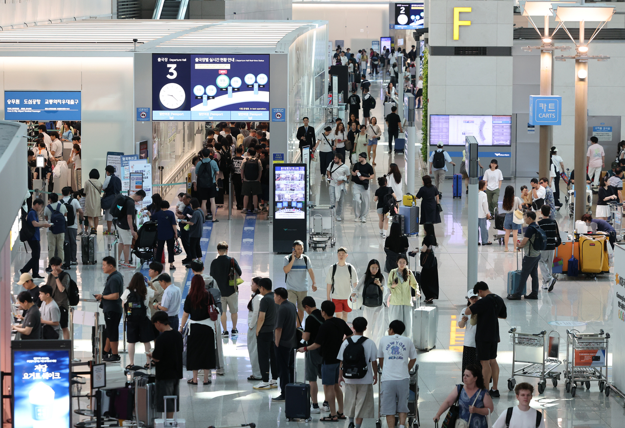 As the peak summer vacation season gets underway, passengers crowd the departure hall of Terminal 1 at Incheon International Airport on Saturday morning. (Newsis)